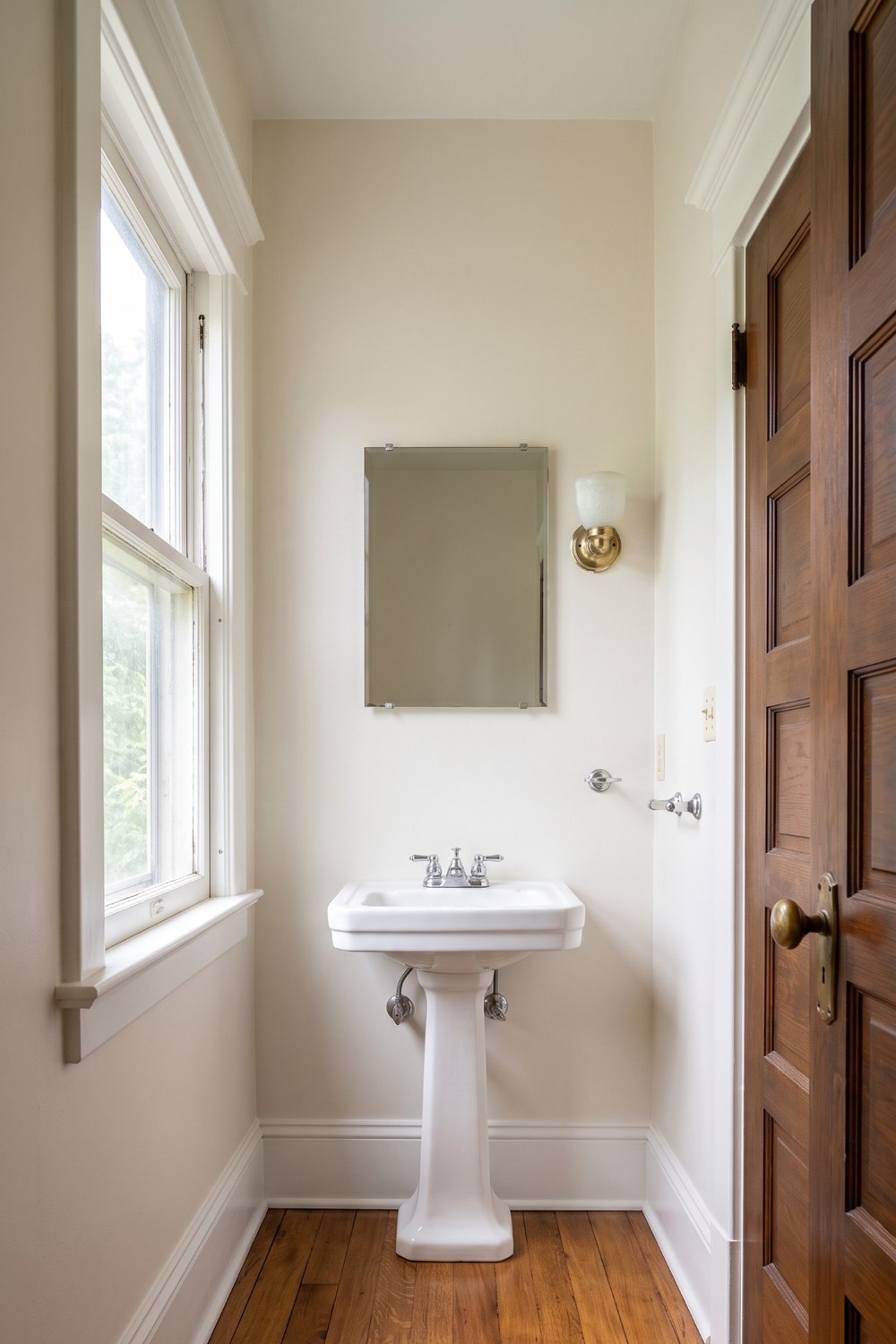 Powder room before — plain white walls and pedestal sink