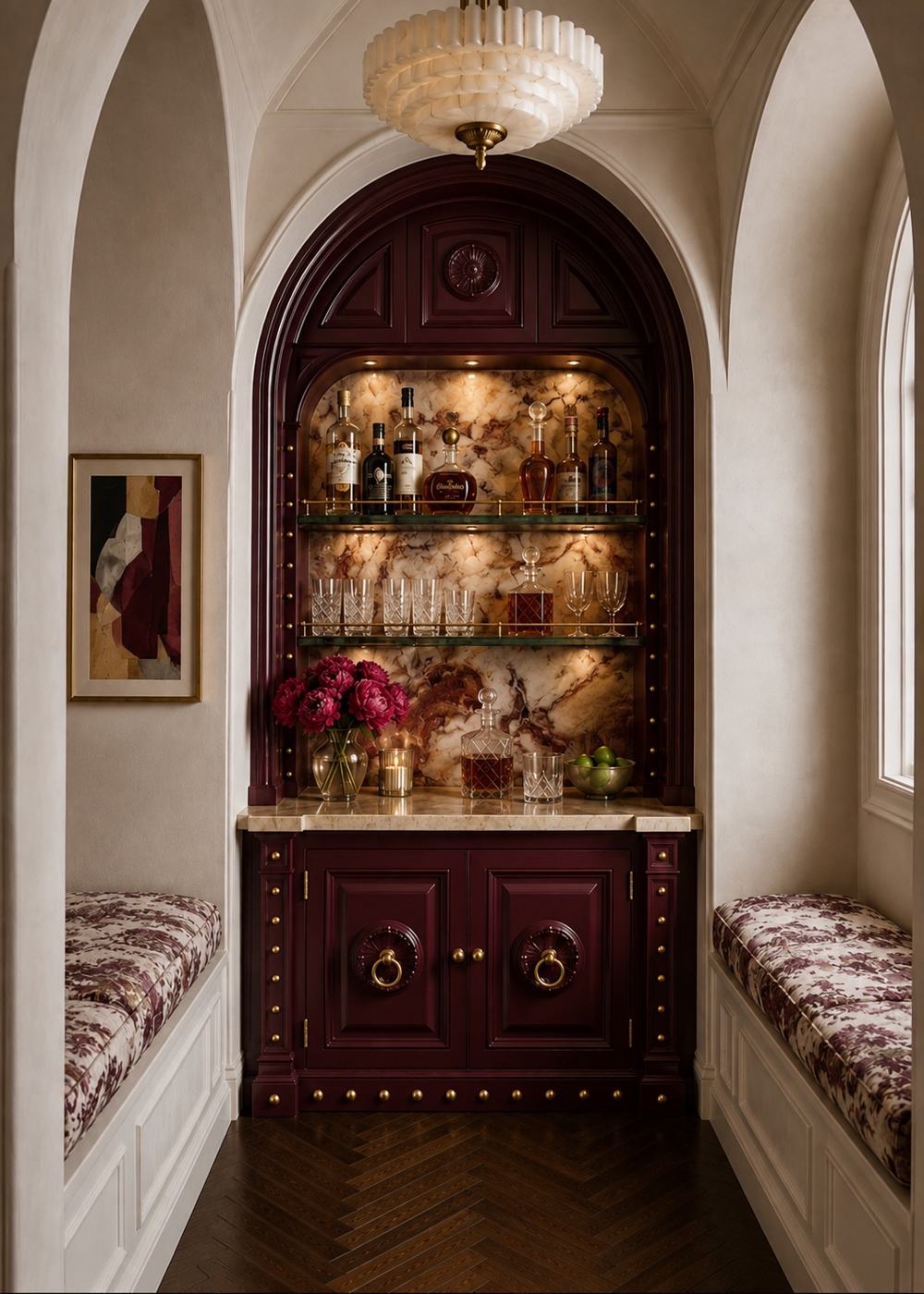 Arched burgundy bar cabinet set into a cream hallway, with lit glass shelves, a marble counter and two window seats in burgundy toile