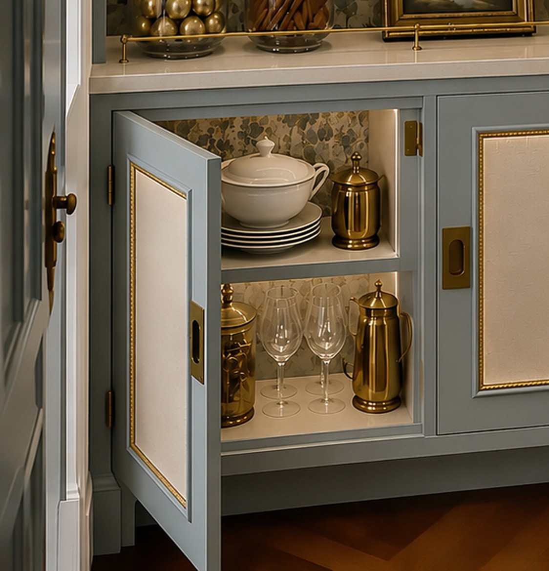 Open cabinet door showing linen-panelled inset front with brass bead trim and brass hardware